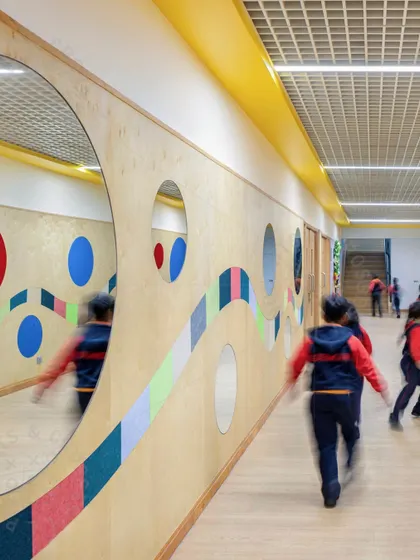 Students walking down a corridor with a dynamic, colorful wall design at GD Goenka Public School. The motion blur captures the energy of the space, which is designed to be more than just a simple passageway.