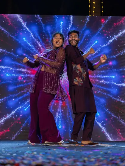 A fun, back-to-back dance pose by the couple on the Sangeet stage, showing their playful chemistry.