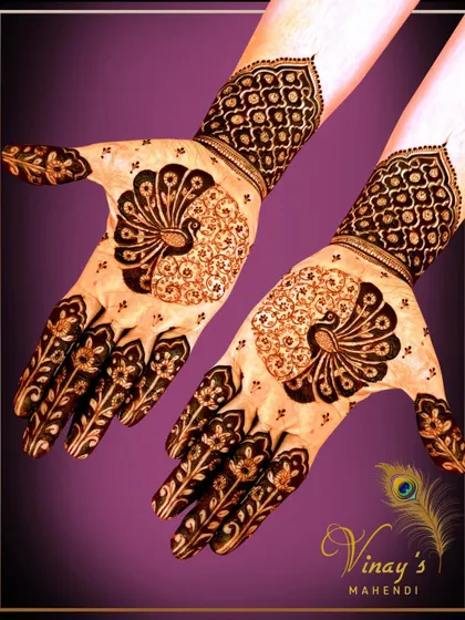 A striking back-of-hand design using negative space to highlight a beautiful peacock motif. The finger designs mimic floral vines.
