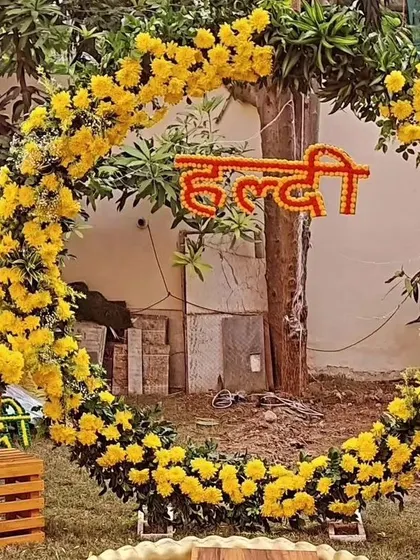 An outdoor Haldi photo frame made from a large ring of yellow marigolds. This simple yet beautiful installation is perfect for capturing memories in a natural setting.