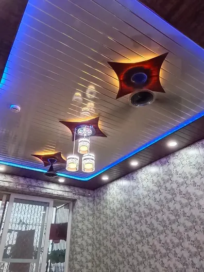A PVC ceiling with integrated blue LED strip lights and decorative fixtures, offering a modern and colorful lighting solution.