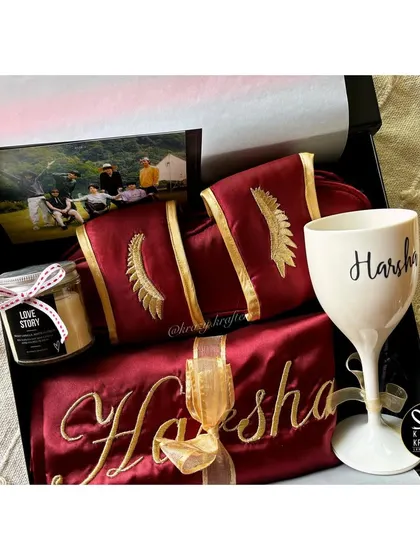 A luxurious hamper for the bride-to-be, featuring a custom-embroidered maroon satin robe and slippers, a personalized wine glass, and a scented candle.