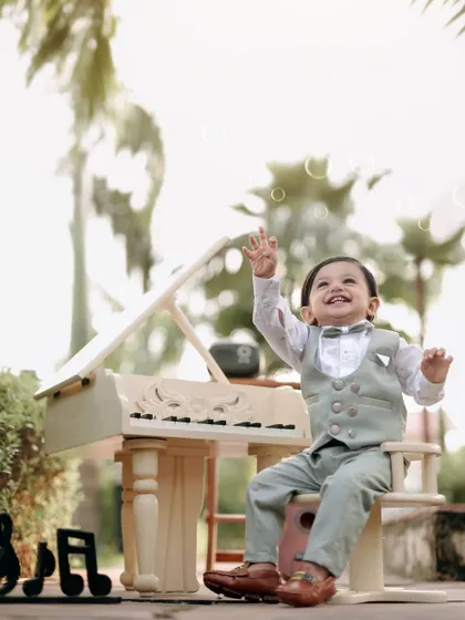 The joy of music and bubbles. This little boy's face is lit up with happiness as he reaches for bubbles during his outdoor piano photoshoot.