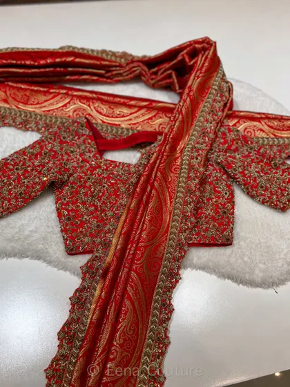The beauty of a bridal trousseau lies in its details. This ensemble features a fully handworked red blouse with zardozi and sequin detailing, paired with a rich Banarasi dupatta that has an ornate paisley weave, making it a true heirloom piece.