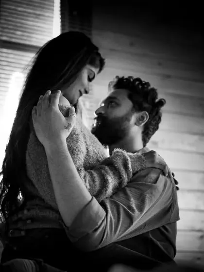 An intimate black and white pre-wedding photo, capturing the deep connection and emotion between a couple in a softly lit room.