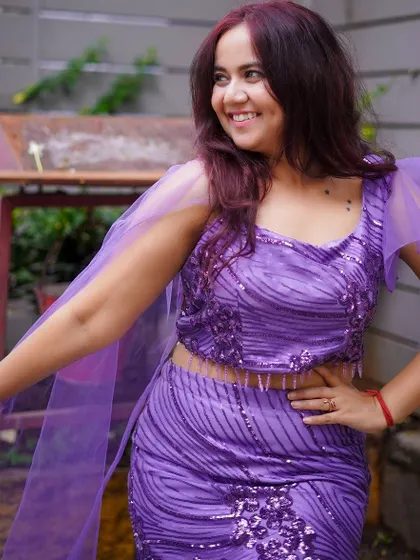 A beautiful purple sequined two-piece gown with a mermaid skirt and delicate cape sleeves. It's a modern and glamorous option for a party or reception.