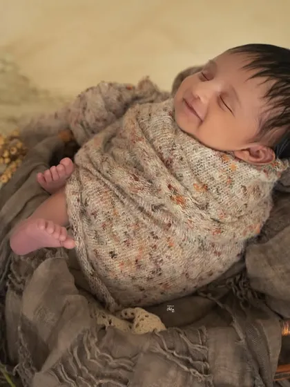 A side view showing the baby's peaceful profile and tiny feet, all wrapped up in a knitted swaddle.