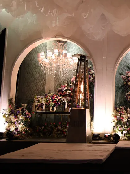 A stage setup with floral-filled arches and crystal chandeliers, creating a beautiful backdrop for performances or speeches.