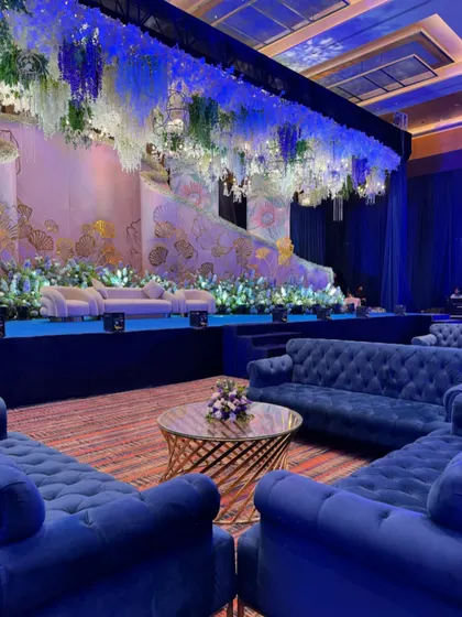 The lounge setup for the reception featured plush blue velvet sofas and a gold spiral coffee table, providing a luxurious and comfortable space for guests to relax and socialize.