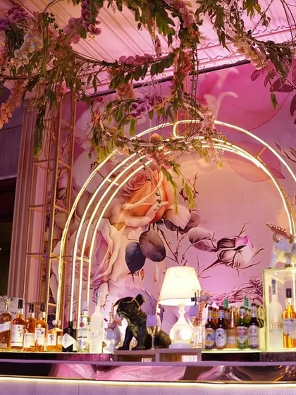 I designed this bar to be a whimsical floral fantasy. A hand-painted backdrop, glowing arches, and a canopy of hanging flowers created a truly enchanting space for cocktails.
