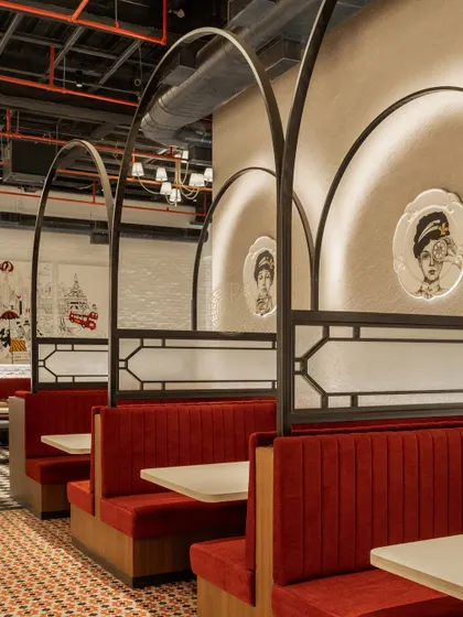A close-up of the custom-designed booths. The metal arches and frosted glass panels provide a sense of privacy while the custom artwork adds a touch of whimsy and character.