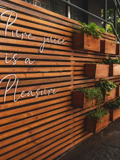 A detail of the juicery's exterior wall, where the brand's tagline is integrated into the wooden slat design. This is an example of how I weave brand messaging directly into the architecture.