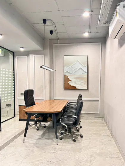 A smaller meeting room or cabin with clean lines and minimalist decor. The textured wall art and simple furniture create a calm and focused environment for discussions.