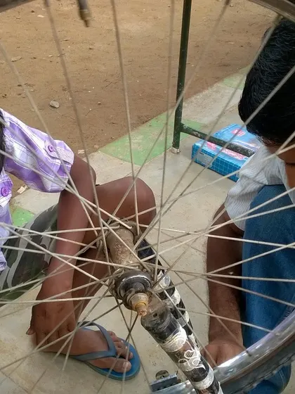 Two boys work together to fix a bicycle wheel. Collaborative learning is at the core of what we do, and it's amazing to see kids helping each other.
