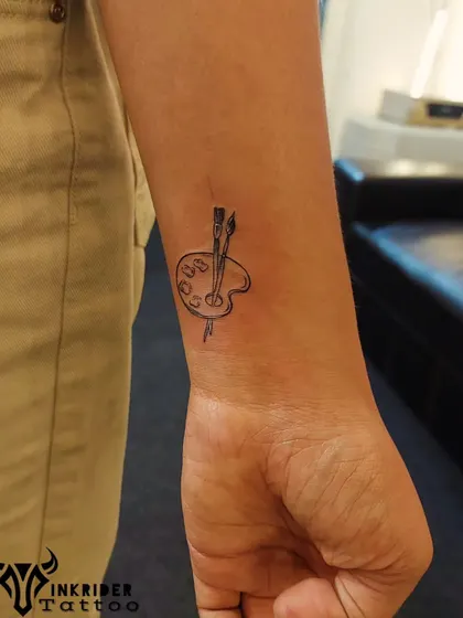 For the artist at heart, a minimalist paint palette and brushes. This fine-line wrist tattoo is a perfect tribute to a creative passion.