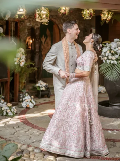 A moment of pure, unscripted laughter between the bride and groom in a beautiful courtyard setting on their wedding day.