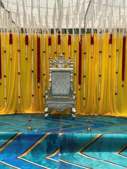 A closer look at the majestic throne and vibrant backdrop for an outdoor ceremony. This view highlights the intricate details of the silver chair and the rich texture of the yellow drapes.