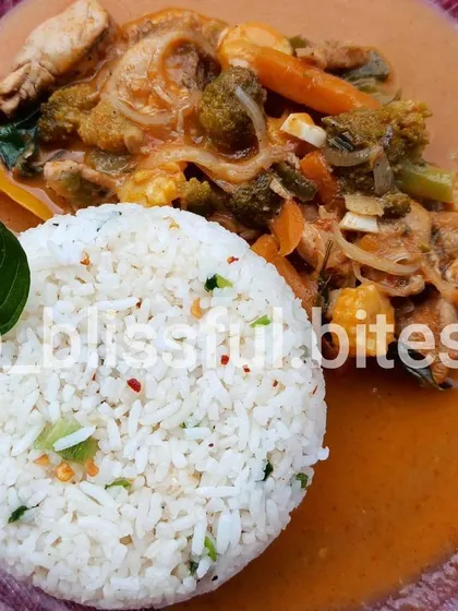 A close-up of the chicken and vegetable Thai Red Curry, showing the creamy coconut-based sauce and fresh ingredients like broccoli and baby corn.