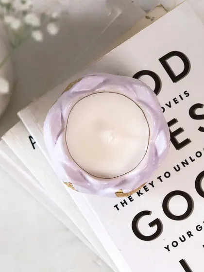 The warmth of our festive candles is all you need for a cozy atmosphere. Here's our lilac lotus jar looking pretty on a stack of books.