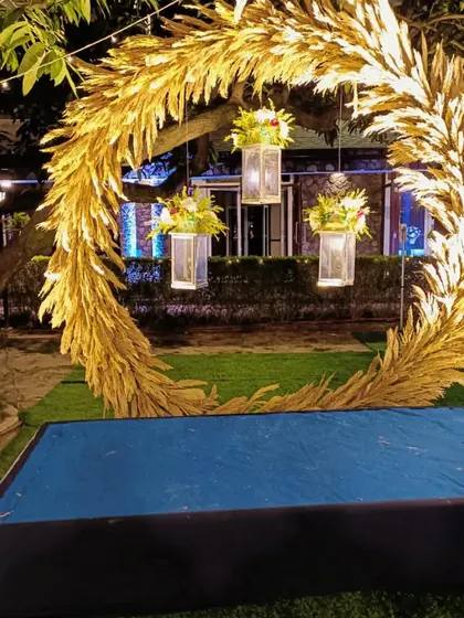A unique circular photo booth arch made of golden pampas grass, perfect for a rustic-glam engagement party.