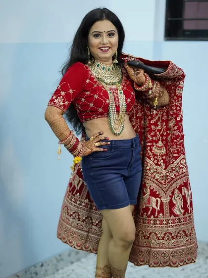 A fun, behind-the-scenes shot of our bride before she gets fully dressed. Her makeup and hair are done, and she's ready to step into her gorgeous red lehenga.