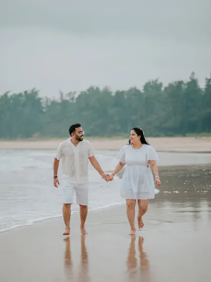 A couple enjoying a romantic walk along the water's edge during their beach pre-wedding shoot.