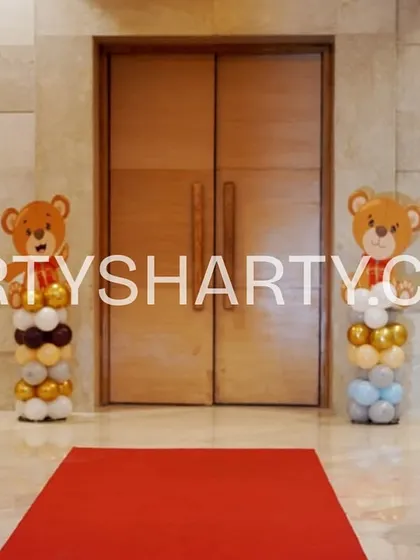A simple yet adorable entrance with a red carpet flanked by four balloon columns, each topped with a different cute teddy bear cutout.