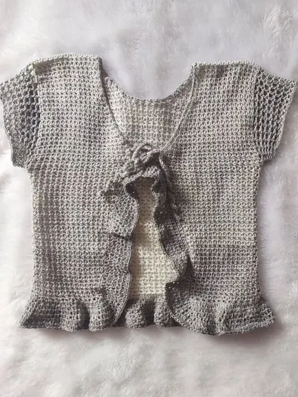A flat-lay of the Orchid Top, showcasing the front tie and ruffled details.