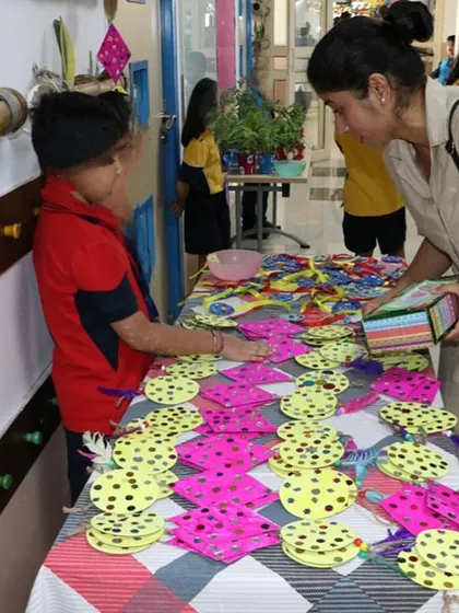 During Shiv Nadar School's "Joy of Sharing Week," a young student sells handmade crafts to a parent to raise funds for our environmental projects.