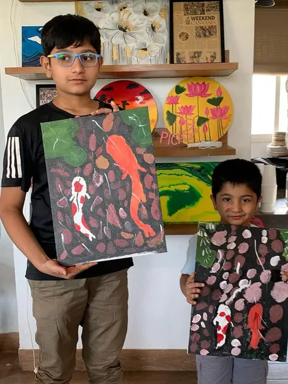 Two young brothers proudly showing off their koi fish paintings from a workshop last year. It's a fin-tastic memory.