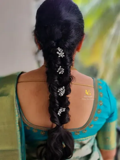 An elegant and simple braided hairstyle for Mallika's housewarming event, accented with delicate white floral clips.