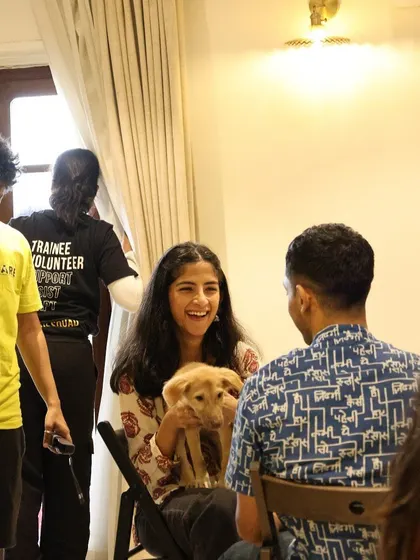 A participant laughs while holding a puppy, sharing a happy moment with a friend at our Bangalore workshop.