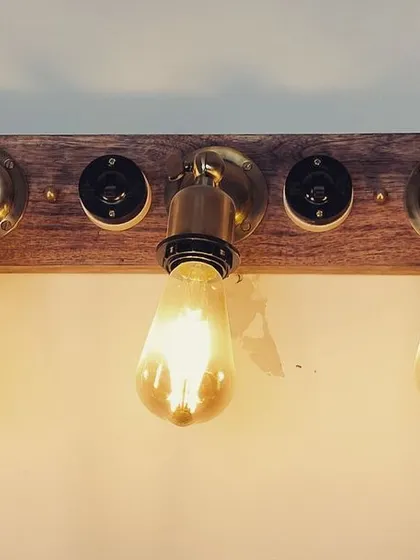 The same rustic light fixture, turned on. The warm glow of the Edison bulbs creates an instantly cozy and inviting atmosphere, perfect for a hallway, bathroom, or above a dining table.