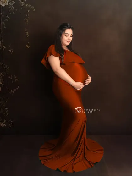A classic side-profile portrait in a beautiful rust-colored gown. The dark, moody background makes the color of the dress pop.