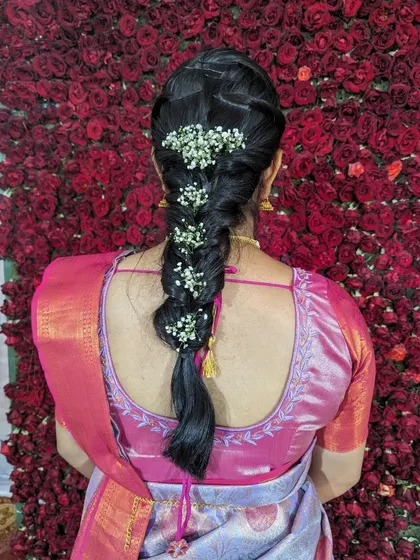 A close-up of a classic fishtail braid adorned with fresh flowers. This is a timeless hairstyle for traditional events, perfectly complementing a silk saree.