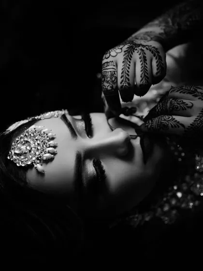 A stunning, artistic black and white close-up of the bride, focusing on her intricate henna and makeup. A true work of art.