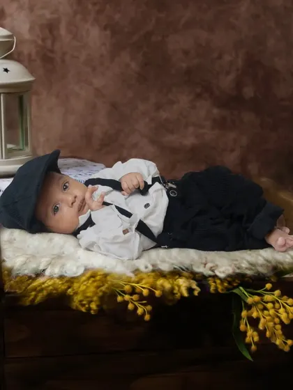 A vintage-style portrait of a baby boy dressed in a classic outfit with a newsboy cap. I use props like this antique-style lantern to add character to the photos.