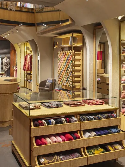 The display furniture at Ahujasons is entirely bespoke, designed to showcase the products beautifully and functionally. This glass-topped counter with pull-out drawers allows for easy viewing of delicate shawls and scarves, blending aesthetics with practical retail needs.