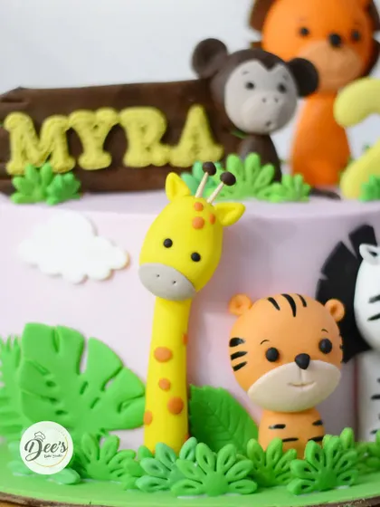 A cute and cuddly jungle animal cake for a second birthday. This cake features adorable, hand-sculpted fondant animals like a giraffe, tiger, and monkey.