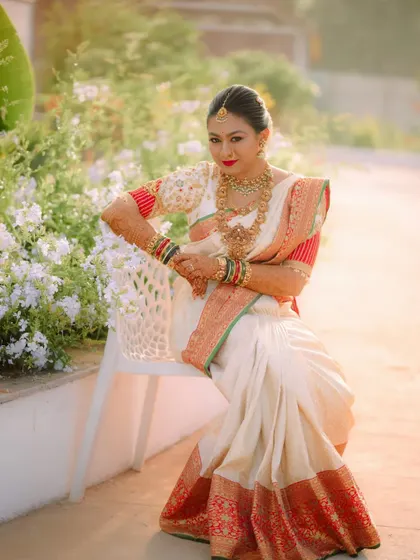 The bride posing gracefully, her red and white saree creating a striking visual.