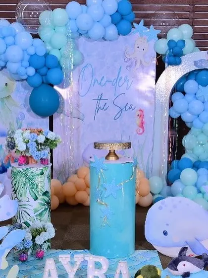 The central part of the 'One-der the Sea' decor, featuring a 'One-der the Sea' backdrop, themed plinths for the cake, and cute whale and octopus props.