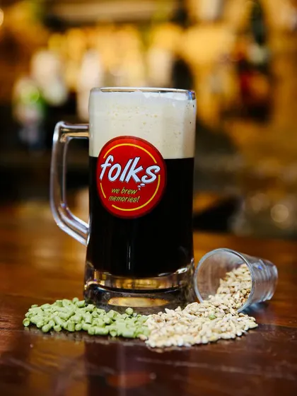 A full mug of a dark craft beer from Folks brewpub. The composition is clean and direct, with the blurred background of the bar adding authentic atmosphere.