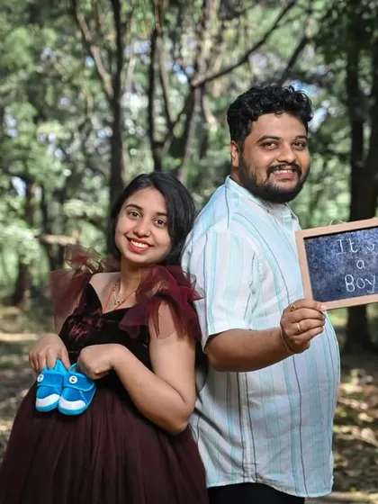 Celebrating with cute props like baby shoes. This couple's maternity shoot is made even more special, with the mom-to-be looking radiant in a deep maroon ruffled gown.