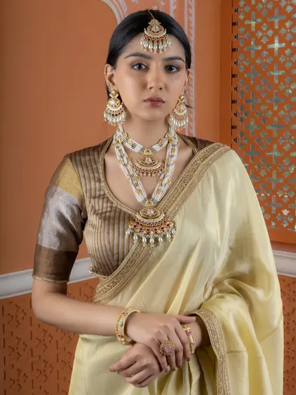 A full-length view of a bride adorned in our layered Kundan and pearl set. This ensemble includes statement chandbali earrings, an ornate maang tikka, and intricate braid accessories.