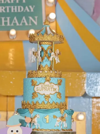 A close-up of the magnificent carousel cake for Vihaan's party. The details are incredible, with a spinning top tier and golden horses, making it a true showstopper.
