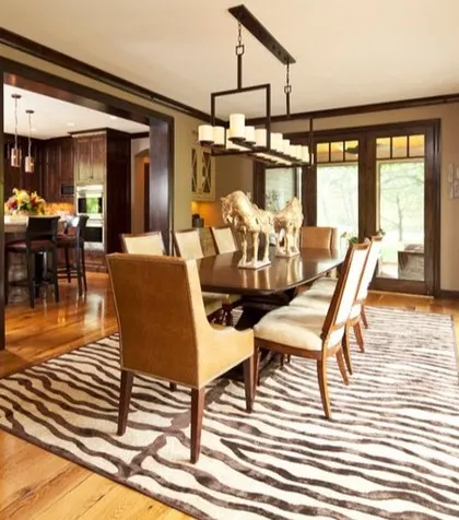A transitional dining room with an animal print rug, a modern light fixture, and large glass doors that open to a view of the outdoors.