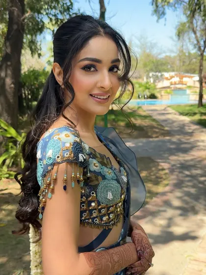 A fresh and vibrant look designed for a Haldi ceremony, breaking away from the traditional yellow. The focus here is on bright, happy makeup with a flawless base and softly defined eyes, letting the intricate blue outfit shine.