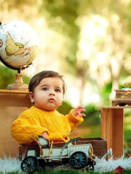 A focused expression as he plays with a vintage toy car during his outdoor adventure photoshoot.