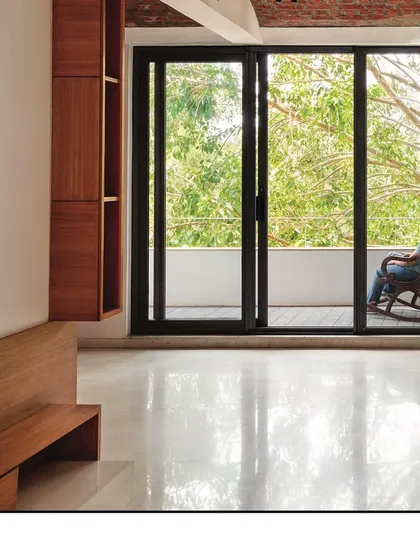 A close-up of the connection to the outdoors, where large glass doors slide away to merge the living room with the balcony and the surrounding nature.