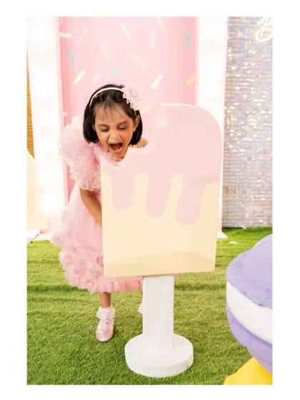 The birthday girl takes a pretend bite out of a giant ice cream prop. Our interactive props make for the cutest photos.